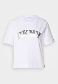 Balta trumpa marškinėliai, pagaminti iš medvilnės, su sidabro metaliniu spaudiniu, kuriame u�žrašyta "DKNY" ir "New York" ryškiais, blokuotais rašmenimis.