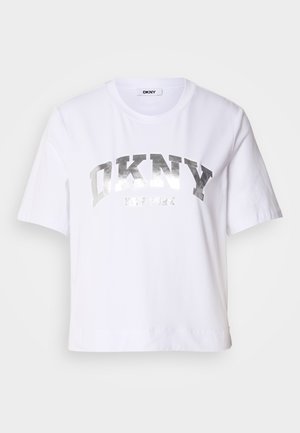 Balta trumpa marškinėliai, pagaminti iš medvilnės, su sidabro metaliniu spaudiniu, kuriame užrašyta "DKNY" ir "New York" ryškiais, blokuotais rašmenimis.