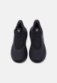 Μαύρα αθλητικά παπούτσια χωρίς κορδόνια με υφασμένο επάνω μέρος με υφή, ταινίες έλξης στη φτέρνα και διακριτικές λεπτομέρειες με το εμπορικό σήμα στις εξωτερικές πλευρές.