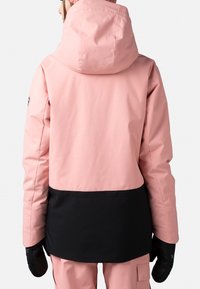 Rosa vattentät jacka med svart nedre del och huva. Har långa ärmar och handskar, lämplig för vinteraktiviteter.