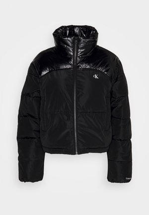 Juoda pūkinė striukė su blizgia viršutine dalimi, užtrauktuku, aukštu apykakle ir elastingomis rankogaliais. Calvin Klein logotipas ant krūtinės.