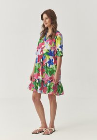 Bloemrijke shift jurk met roze, blauwe en groene tinten, een gelaagde rucheszoom, korte mouwen en een V-halsontwerp. Gewone stoftextuur.