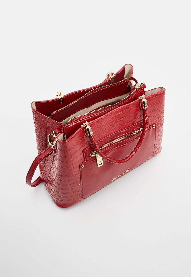 Borsa a tracolla in finta pelle di coccodrillo rossa con hardware dorato, doppie tasche con zip e una tasca frontale. Manici piatti in alto.