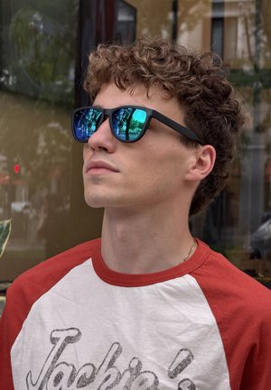 Ochelari de soare negri cu lentile reflectorizante albastre; ramă mată; tricou raglan alb și roșu cu text retro pe față.