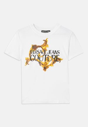 Hvit bomull t-skjorte med et gull- og brunt barokk mønster, med "VERSACE JEANS COUTURE" tydelig vist i svart skrift.