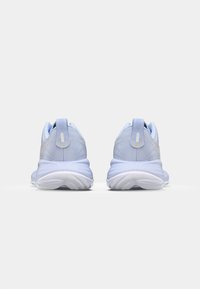 Baskets de sport bleu clair avec une tige en textile lisse, semelle en caoutchouc blanc rembourrée et détails logo subtils au niveau du talon.
