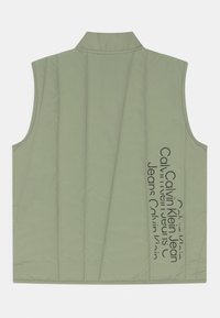 Jasnozielona kamizelka wyściełana z wysokim kołnierzem i pionowym przeszyciem. Posiada czarny nadrukowany tekst z boku. Bez rękawów. Gładka tekstura.