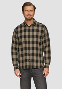 Zwart en bruin geruite shirt gemaakt van stof met een gestructureerde afwerking; heeft een knoopsluiting aan de voorkant en lange mouwen, met een borstzak aan de linkerkant.