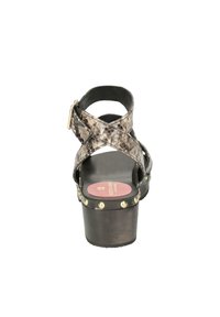 Black and brown snake-patterned sandal with crossed straps, a chunky heel, and gold studs along the sole. Pink insole logo visible.