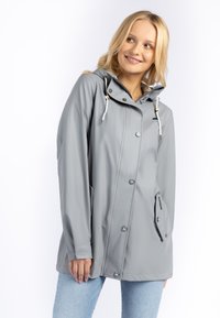 Giacca impermeabile grigia con cappuccio, bottoni, coulisse e tasche frontali. Caratterizzata da una texture liscia e una vestibilità comoda.