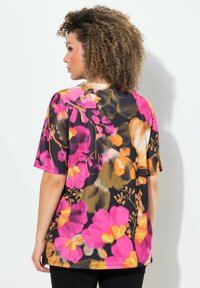 Top de manga corta con fondo negro, que presenta grandes patrones florales en tonos rosa, naranja y amarillo. Tejido suave con un ajuste relajado.