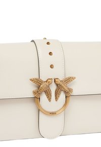 Witte leren handtas met een gouden ronde accent met twee vogelmotieven en decoratieve studs langs de klep.