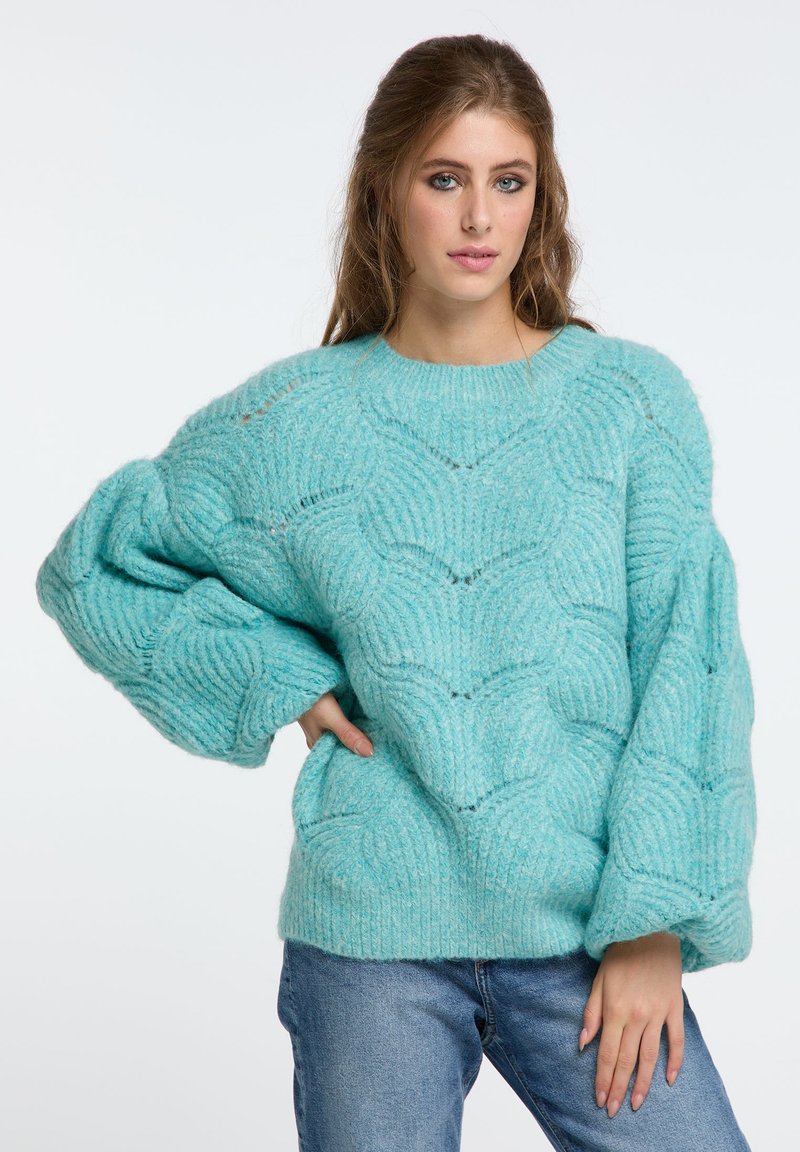 Türkiser, übergroßer Pullover aus gestricktem, strukturiertem Material mit einem Wellenmuster, breiten Ärmeln und einem Rundhalsausschnitt.