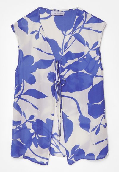 Bloemige mouwloze blouse van transparante stof, met een blauw patroon op een witte achtergrond, v-hals en strikdetails aan de voorkant.
