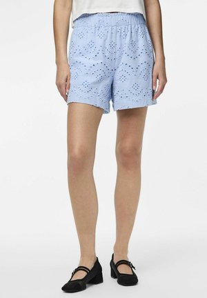 Lyseblå bomuldsshorts med broderet hulmønster, elastisk talje, og afsluttede kanter, parret med sorte, lave hæle.