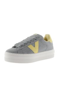 Sneaker in suede grigio con accenti gialli, lacci testurizzati e suola in gomma bianca. Presenta un logo giallo ben visibile sul lato.