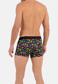 Herrenslips i boxer-stil med ett färgglatt fjärilsmönster på en svart bakgrund. Tillverkade av glatt, elastiskt tyg med ett svart midjeband.