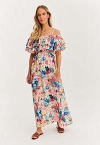 Maxi sukienka w kwiatowe wzory w kolorach różowym, niebieskim i żółtym; ramiączka bez ramiączek z falbaną; lekki materiał; podkreślona talia; płaskie sandały.