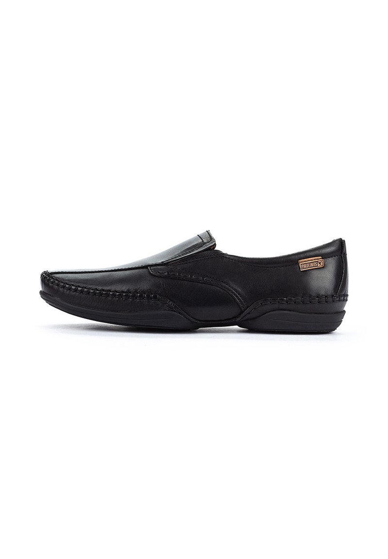 Zapato negro de cuero sin cordones con un acabado suave, costuras decorativas a lo largo de los lados y una sutil etiqueta de marca en la parte superior.