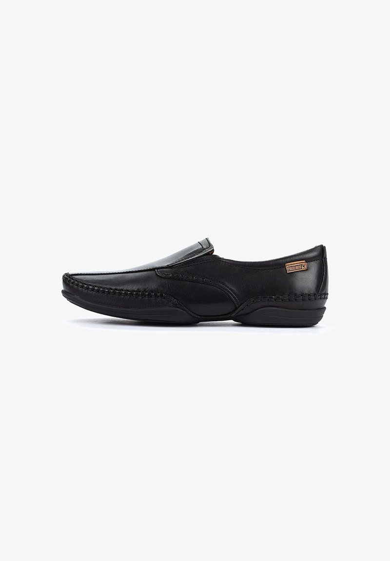 Zapato negro de cuero sin cordones con un acabado suave, costuras decorativas a lo largo de los lados y una sutil etiqueta de marca en la parte superior.