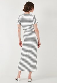 Abito maxi a righe con maniche corte, un corpetto aderente e una lunga gonna. Realizzato in tessuto leggero bianco con strisce nere.