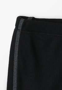 Leggings sportivi neri con una vita testurizzata, caratterizzati da una cucitura grigia lungo il lato per un tocco di dettaglio in più. Tessuto morbido ed elastico.