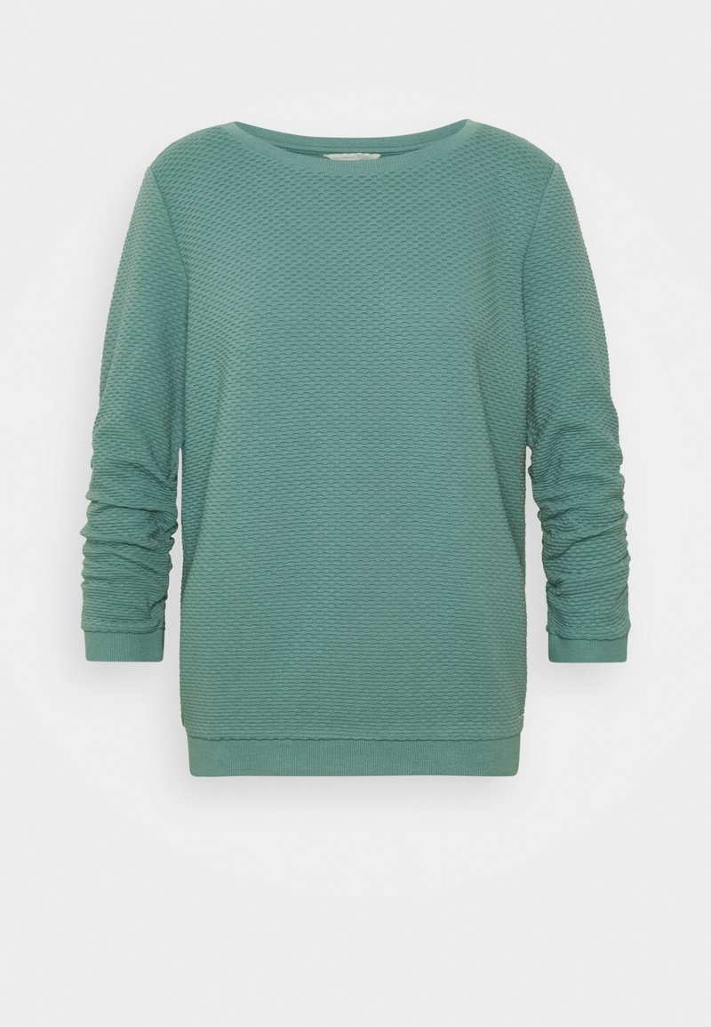 Sweat-shirt teal à manches longues avec col rond, motif nid d'abeille texturé, poignets et ourlet côtelés, présenté sur fond blanc.