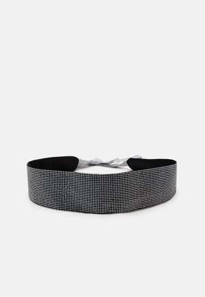 Black belt featuring a grid of silver studs, with a smooth texture and a central gray ribbon for tying. The design is wide and flat.
