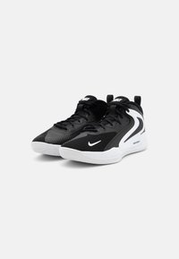 Scarpe da ginnastica nere con una tomaia testurizzata, logo Nike bianco e suola in gomma. Presentano pannelli in rete e un tappo di estrazione sul tallone.