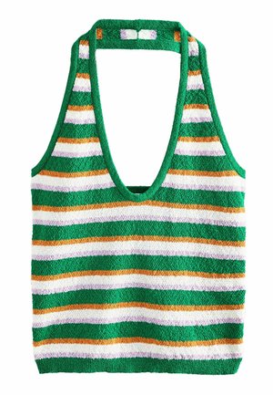 Kobieta z długimi ciemnymi włosami, ubrana w zielony, biały, pomarańczowy i różowy kombinezon na szyję typu halter z paskami, stojąca przy białej, zakrzywionej ścianie.