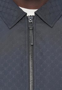 Ναυτικό μπουφάν με φερμουάρ μπροστά, με υφασμένη υφή, μυτερό γιακά και ασημένιο φερμουάρ. Διαθέτει απαλό ύφασμα και αντίθετη ραφή.