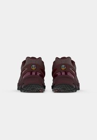 Burgundowe buty sportowe z siateczkowej cholewki, gumową podeszwą i błyszczącymi akcentami. Posiadają okrągły czubek i wyprofilowaną piętę. Logo z boku.