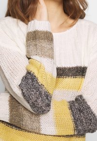 Maglione a maglia con strisce orizzontali in crema, giallo, marrone e grigio. Tessuto con texture, vestibilità ampia con polsini a coste e collo rotondo.