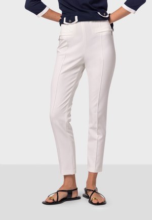 Witte broek met een slim fit, voorzien van zijzakken, strakke lijnen en een gladde textuur. Gecombineerd met zwarte platte sandalen.