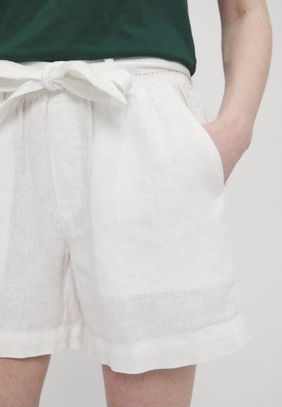 Hvite linshorts med knyttet midje, sidelommer og avslappet passform. Myk tekstur med en litt rynket overflate.