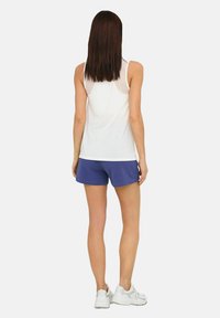 Hvid ærmeløs top med en meshindsats, parret med blå shorts. Model bærer hvide sportsko. Bagfra, glat tekstur, afslappet design.