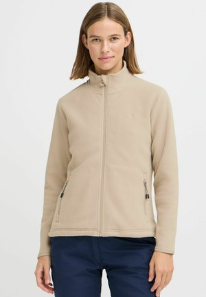 Veste en polaire beige avec fermeture éclair sur le devant, col montant et deux poches latérales zippées. Texture lisse avec une discrète marque sur la poitrine.