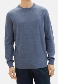 Pull à col rond en tricot texturé bleu, avec manches longues et poignets côtelés. Détail logo subtil sur la poitrine. Matière douce de poids moyen.
