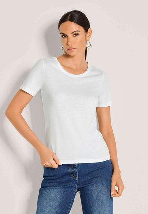 Weißes T-Shirt mit kurzen Ärmeln und rundem Ausschnitt, aus glattem Stoff. Kombiniert mit dunkelblauen Jeans, die eine lockere Passform zeigen.