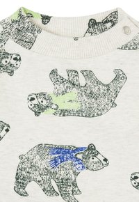 Ljusfärgad t-shirt med illustrerade björnar i svart och grönt, där en björn bär en blå scarf. Ribbad krage med knäppning.