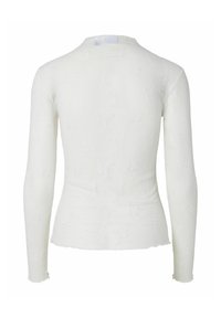 Haut blanc ajusté à manches longues avec un motif floral texturé subtil, col rond, et ourlet et poignets légèrement froncés, vu de dos.