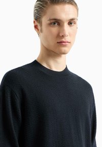 Maglione lavorato a maglia blu navy con colletto rotondo, dotato di un motivo a spina di pesce testurizzato e dettagli a coste nei polsini.