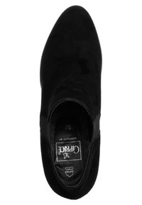 Zapato de ante negro con puntera redonda, paneles laterales elásticos y una plantilla texturizada con el nombre de la marca "Caprice" visible.