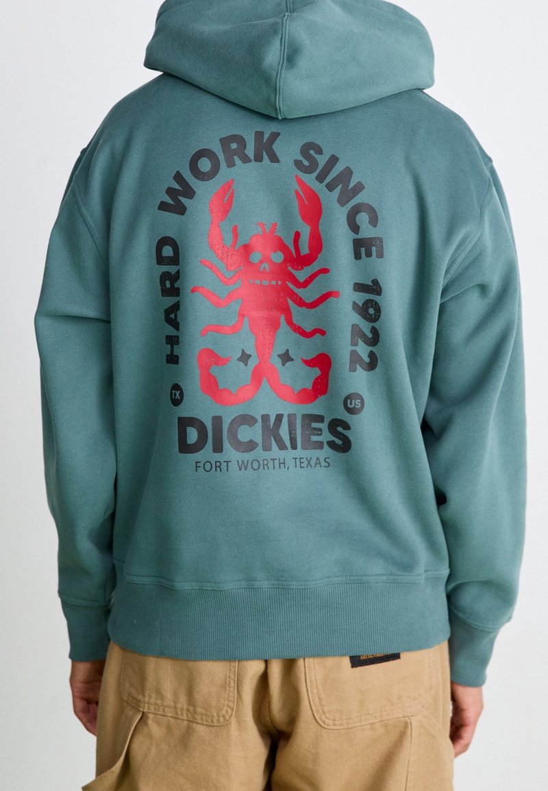 Sudadera con capucha verde con bolsillo frontal tipo canguro, con un gran gráfico de una langosta roja y texto en la espalda. Material suave, mezcla de algodón.