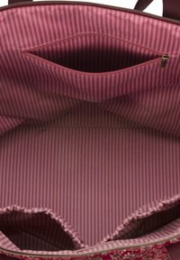 Roze stoffen tas interieur met verticale strepen; heeft een ritsvak en elastische compartimenten voor organisatie. Zachte textuur, ruime indeling.
