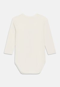 Body pour bébé à manches longues de couleur crème avec col rond et fermeture à pression en bas, vu de dos sur un fond uni.