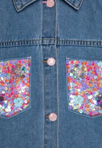 Jeansjack met twee zakken versierd met pailletten en kleurrijke bloemmotieven. Lichtblauwe stof met roze glittersknopen.