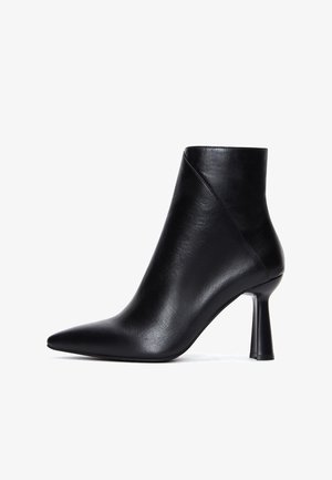 Botín de cuero negro hasta el tobillo con punta afilada y un tacón elegante y cónico. Presenta un acabado suave con costuras mínimas y un diseño moderno.