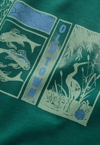 Grüner Stoff mit hellblauen Grafiken von Koi-Fischen, einem Reiher und dem Text "ALTSTADT", mit aufwendigen Mustern und Texturen.