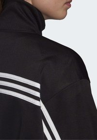 Black sweatshirt with a high neck, featuring white striped accents on the shoulders, made of smooth, matte fabric.